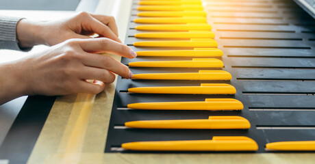 Female hands with yellow ballpoint pens, mock up. Large format UV flatbed printer for printing on...