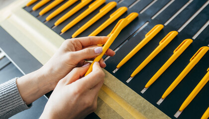 Female hands with yellow ballpoint pens, mock up. Large format UV flatbed printer for printing on...