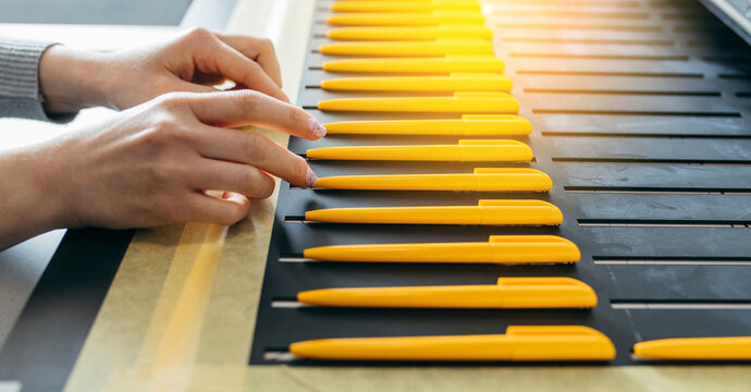 Female hands with yellow ballpoint pens, mock up. Large format UV flatbed printer for printing on all kind of rigid material. 