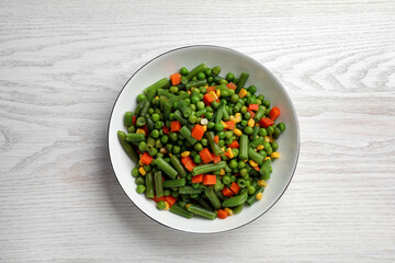 Tasty vegetable mix in bowl on white wooden table, top view