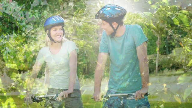 Animation of leaves over smiling caucasian couple talking with bicycles