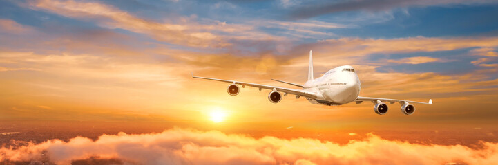 Wide panoramic view, banner of a flying passenger airplane four jet engine on a picturesque sunrise...