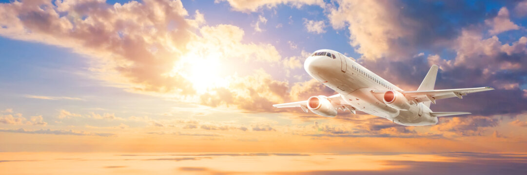 Wide broad panoramic banner of a flying passenger civil jet on a picturesque sunset dawn sky, travel trip.