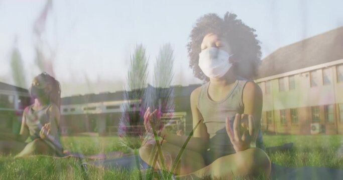 Animation of flowers over diverse children with face masks practicing yoga and meditating