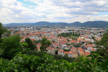 Fototapeta premium Panoramic view from the Castle Montain to the city of Graz, Austria with the Graz hills in the background at cloudy sky