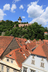 Fototapeta premium View over the roofs of the city of Graz, Austria to the famous clock tower at the castle mountain