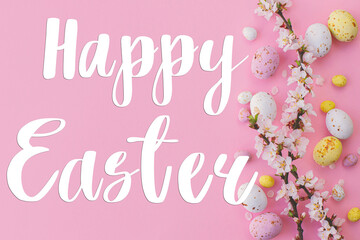 Happy Easter greeting card. Happy Easter text and colorful Easter chocolate eggs and cherry blossoms border on pink background flat lay. Seasons greeting card, handwritten lettering