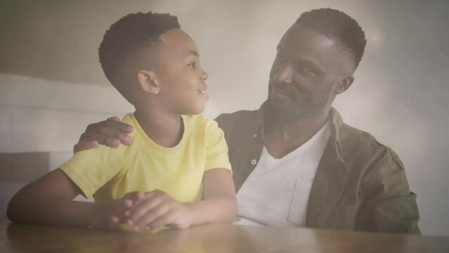Animation of lights over happy african american father and son talking