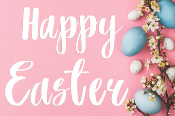 Happy Easter greeting card. Happy Easter text and modern stylish easter eggs and flowers flat lay on pink background. Seasons greeting card, handwritten lettering