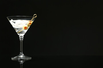 Martini cocktail with ice and olives on dark background. Space for text