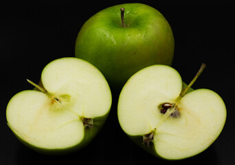 Fresh green apple and sliced isolated on black background.