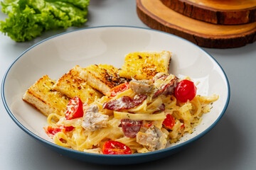 homemade fettuccine pasta with white cream sauce and garlic bread. fettuccine Carbonara made with eggs, hard cheese, cured pork, and black pepper. Italian food.