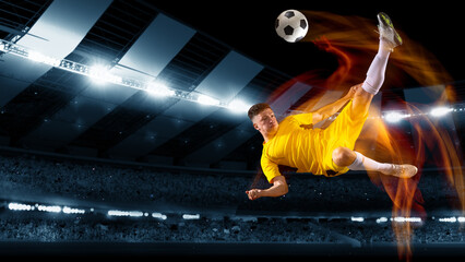 Active professional soccer, football player kick the ball in jump at dark night stadium with flashlights. Sport, competition, championship