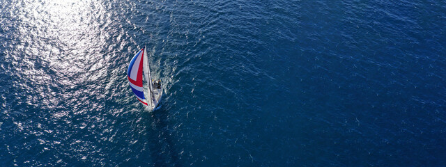 Aerial drone ultra wide photo with copy space of beautiful sailboat with colourful sails cruising...