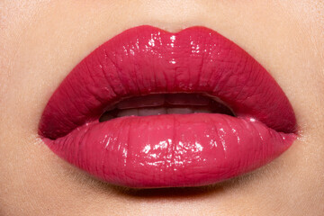 Close-up of beautiful plump female lips with red shiny  lipstick.  Beauty cosmetic concept