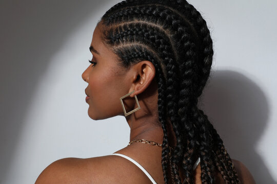 Side close-up of African young woman with braids posing on white background.