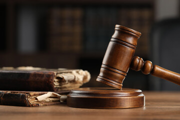 Wooden gavel and antique books on table, closeup