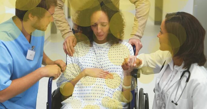 Animation of green spots over biracial pregnant woman talking with doctor and nurse