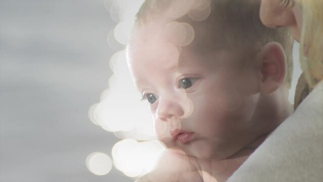 Animation of light spots over caucasian mother holding her baby