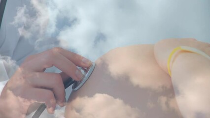 Animation of clouds over caucasian doctor inspecting caucasian pregnant woman
