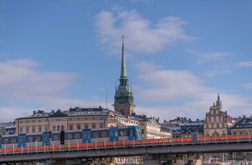 Old subway tram on a bridge at the sluice area at the old town Gamla Stan a snowy spring day in Stockholm