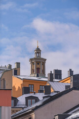 Dorms, chimneys and towers with black tin roofs on old 1700s buildings a snowy spring day in Stockholm