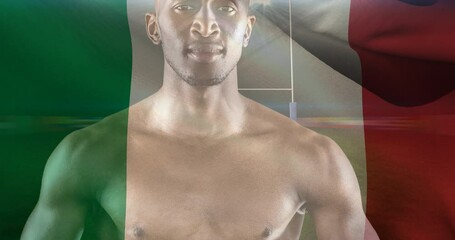 Animation of flag of italy over african american male rugby player with ball at stadium - Powered by Adobe