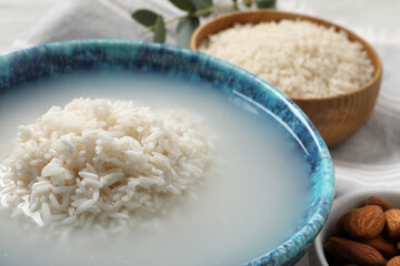 Fototapeta na wymiar Bowl with rice soaked in water on table, closeup