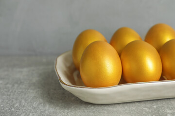 Shiny golden eggs on light grey table, closeup. Space for text