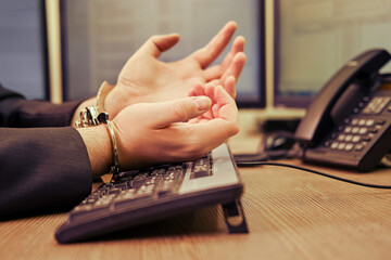A businessman man in handcuffs on his hands is working on a computer keyboard at an office desk,...