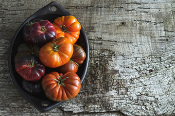 Tray with assorted tomatoes on old wood background. Copy space. - obrazy, fototapety, plakaty