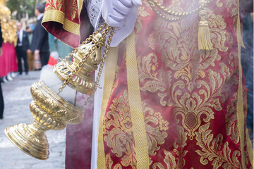 Altar boy or acolyte in the holy week procession shaking a censer to produce smoke and fragrance of...