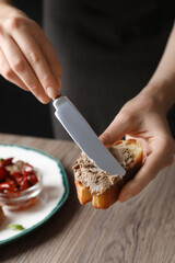 Woman spreading delicious pate onto bread over table, closeup