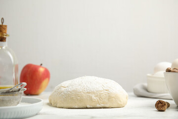 Raw dough, nutmeg seeds and other ingredients for pastry on marble table against white background