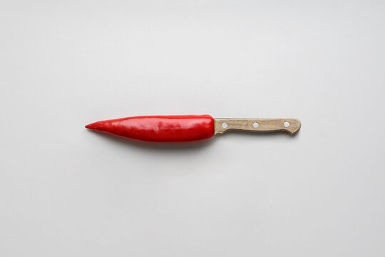 Red hot pepper in the shape of a knife on a gray background with a copy space.