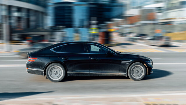 Luxury business car Genesis G80 driving the streets. Motion image of black korean car running on the city road