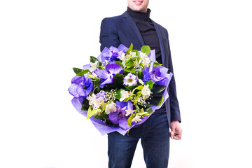 funny handsome young man with dark suit with a beautiful bouquet in the hands of white and purple flowers isolated on a white background