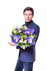 funny handsome young man with dark suit with a beautiful bouquet in the hands of white and purple flowers isolated on a white background