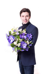 funny handsome young man with dark suit with a beautiful bouquet in the hands of white and purple flowers isolated on a white background