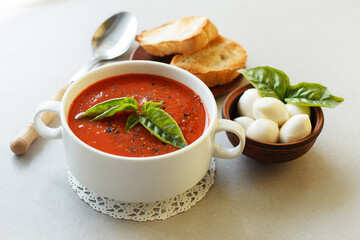 Italian tomato soup with mozzarella and basil and croutons on a lacy napkin.