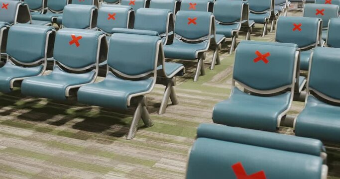 Empty rows of airport seats marked with red signs crosses for distance, no people, departure lounge, waiting room. Social distancing on transport due to COVID-19 pandemic