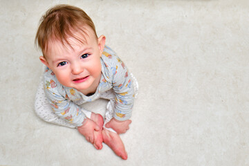 Fototapeta premium Portrait of a crying toddler boy sitting on the floor. Face of an unhappy child with tears in his eyes, copy space
