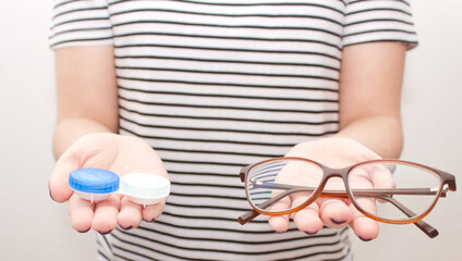 Obraz premium Woman in black-white t-shirt keep contact lens case and glasses. Concept of choice the way vision correction 