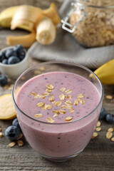 Glass of tasty banana blueberry smoothie with oatmeal on wooden table