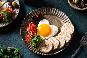 Romantic breakfast - fried eggs in the shape of a heart and olives. Healthy breakfast. Rice cakes with eggs and hamon. Keto diet breakfast. Top view.