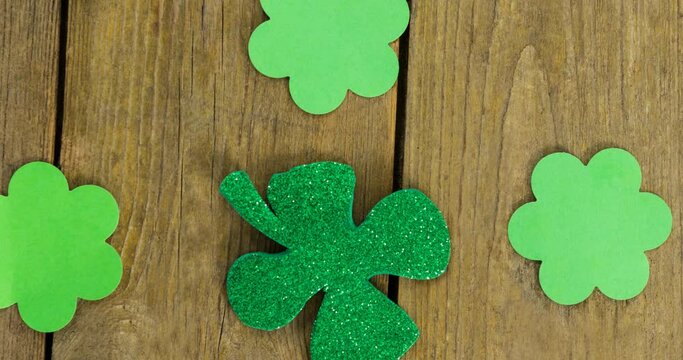 Animation of multiple clover leaves on wooden background