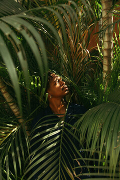 A young black man dressed in blue standing outdoors amongst nature 