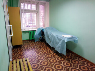 A wheelchair bed covered with a blue sheet, or a stretcher on wheels for transporting bedridden patients along the hospital corridor