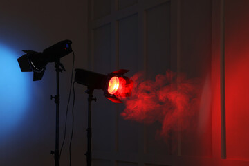 Bright spotlights near wall in dark room, space for text