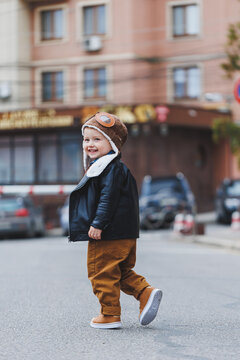 Stylish boy 3 years old in a leather jacket and brown trousers walks on the street. Modern child. Children's fashion. Happy child